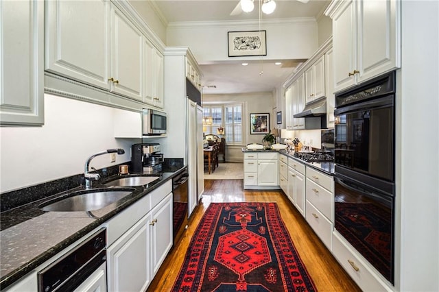 kitchen with wood-type flooring, white cabinetry, dark stone counters, and black appliances