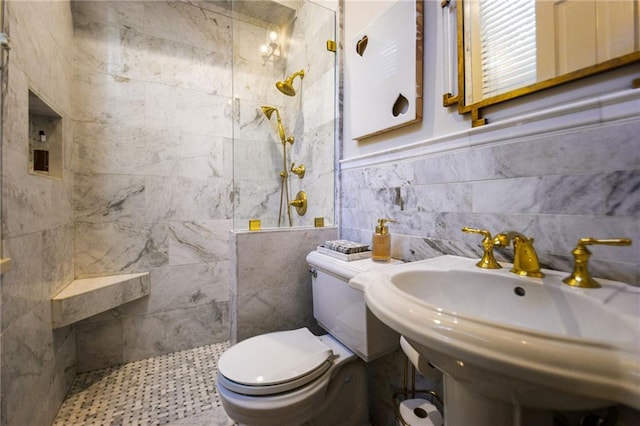 bathroom with tiled shower, toilet, sink, and tile walls