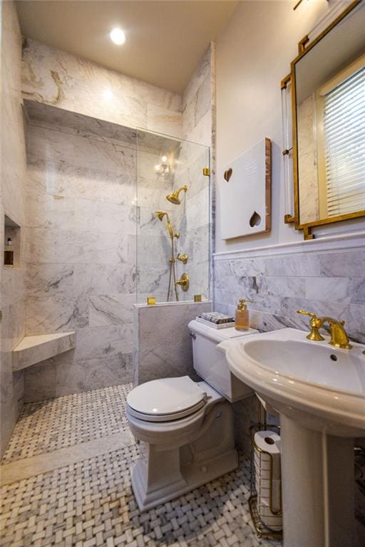 bathroom with tile patterned floors, sink, toilet, tile walls, and a tile shower