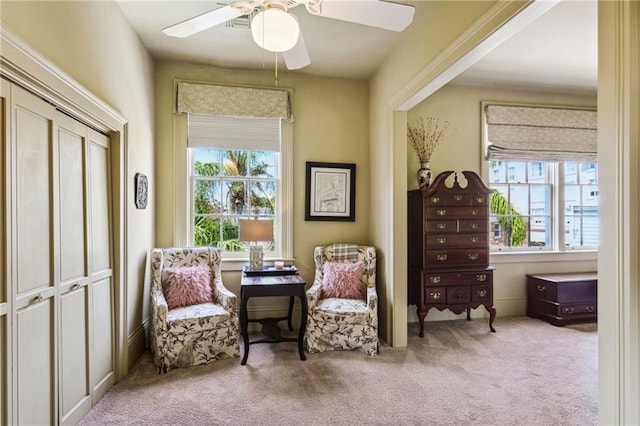 sitting room featuring light colored carpet and ceiling fan