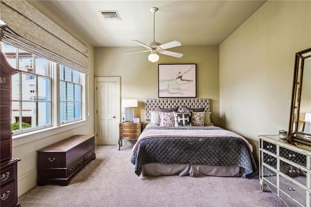 carpeted bedroom featuring multiple windows and ceiling fan