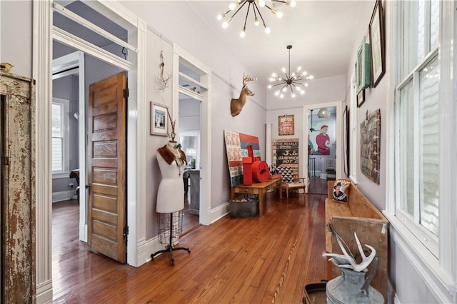 corridor with hardwood / wood-style floors and a notable chandelier