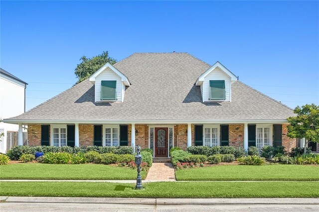 cape cod house featuring a porch and a front yard