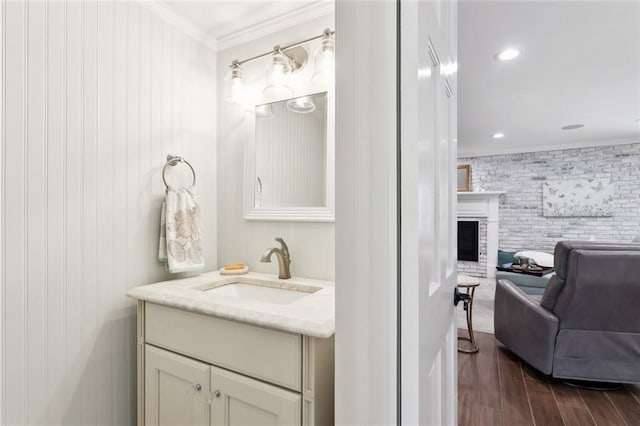 bathroom with hardwood / wood-style floors, a fireplace, vanity, and ornamental molding