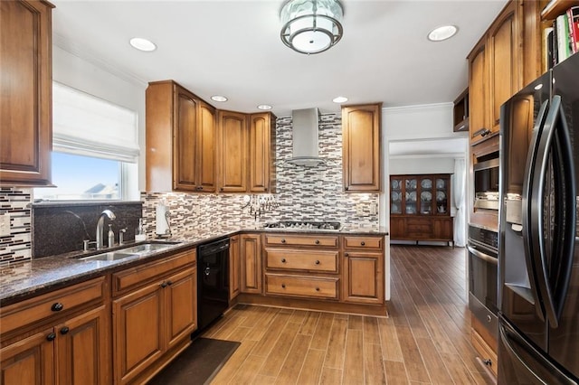 kitchen with decorative backsplash, black appliances, dark stone countertops, wall chimney exhaust hood, and light hardwood / wood-style floors