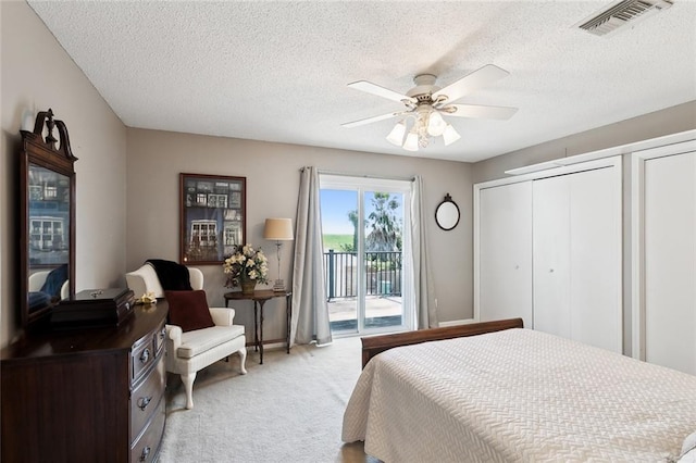 bedroom featuring ceiling fan, access to exterior, a textured ceiling, and light colored carpet