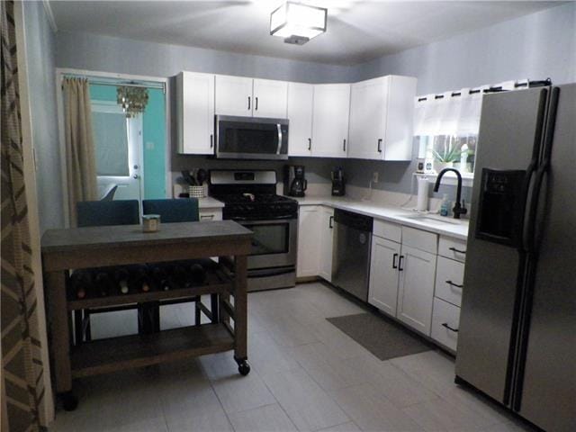 kitchen with appliances with stainless steel finishes, sink, and white cabinetry