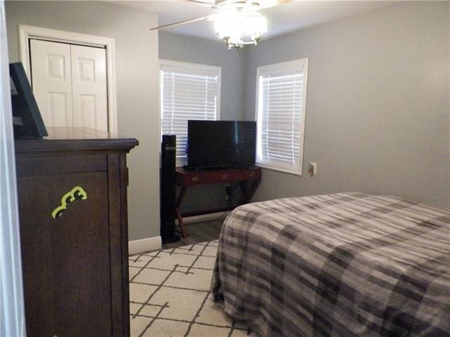 bedroom featuring ceiling fan, light tile patterned flooring, and a closet