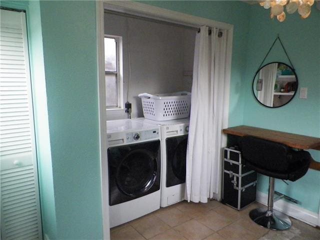 laundry room featuring washing machine and dryer, light tile patterned floors, and a chandelier