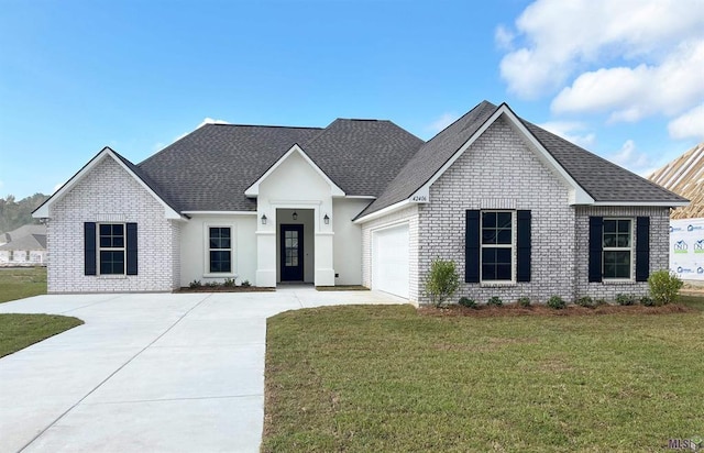 view of front of property featuring concrete driveway, a front yard, a shingled roof, a garage, and brick siding