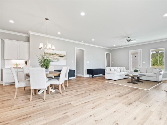 living room with ceiling fan with notable chandelier, ornamental molding, and light hardwood / wood-style floors