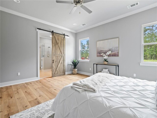 bedroom with crown molding, ceiling fan, hardwood / wood-style floors, ensuite bathroom, and a barn door