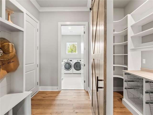 laundry room featuring a barn door, washer and dryer, and light hardwood / wood-style floors