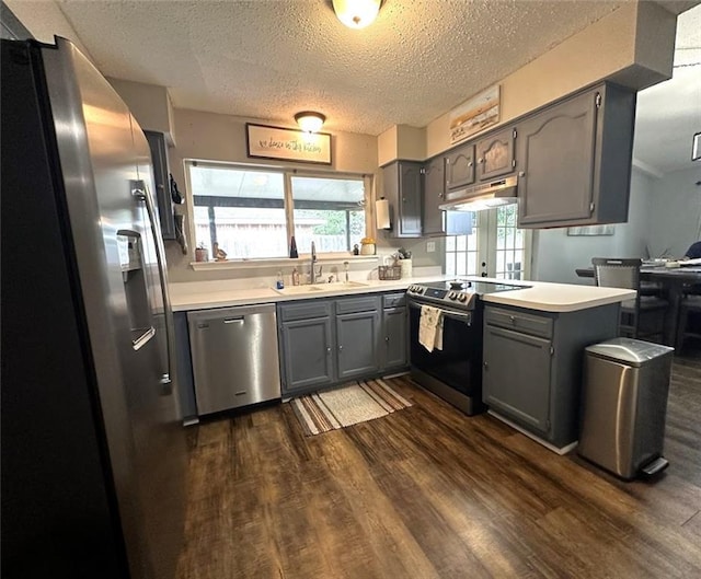 kitchen with stainless steel appliances, light countertops, a sink, and a peninsula