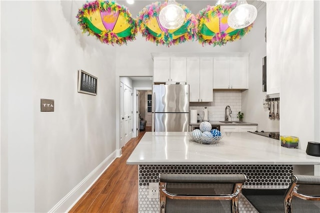 719 St Ann St Unit 2, New Orleans, LA 70116 - kitchen featuring freestanding refrigerator, a sink, backsplash, wood finished floors, and white cabinets