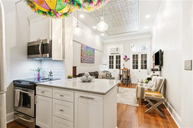 719 St Ann St Unit 2, New Orleans, LA 70116 - kitchen with stainless steel appliances, wood finished floors, white cabinetry, light countertops, and crown molding