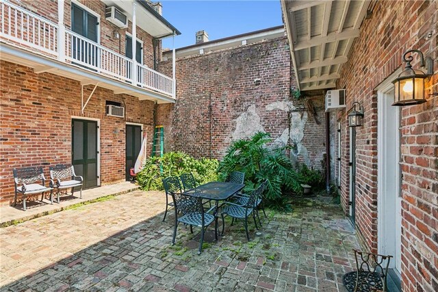 719 St Ann St Unit 2, New Orleans, LA 70116 - view of patio featuring a balcony, outdoor dining area, and an AC wall unit
