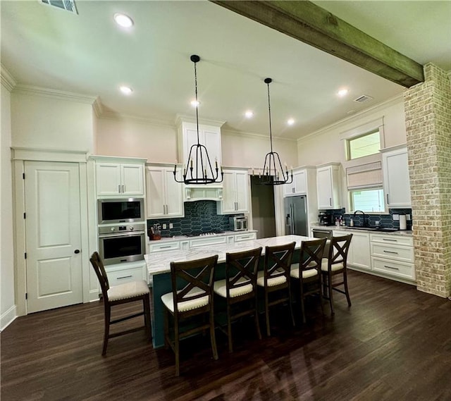 kitchen with tasteful backsplash, appliances with stainless steel finishes, dark wood-type flooring, and a kitchen island