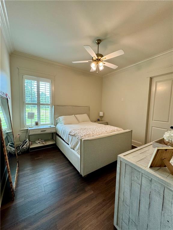 bedroom with ceiling fan, crown molding, and dark wood-type flooring