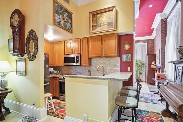 kitchen featuring brick wall, light tile patterned floors, appliances with stainless steel finishes, and tasteful backsplash