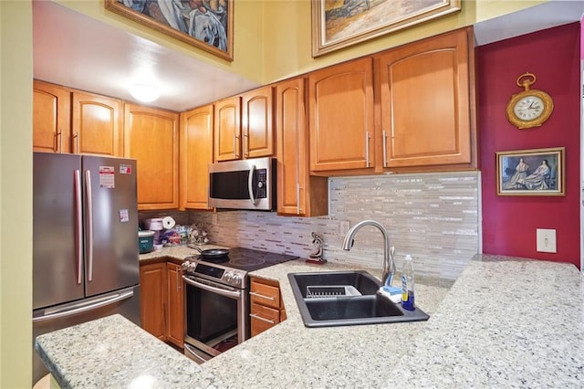 kitchen featuring light stone countertops, stainless steel appliances, tasteful backsplash, and sink