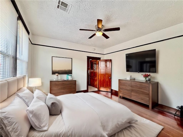 bedroom featuring ceiling fan, light wood-type flooring, and a textured ceiling