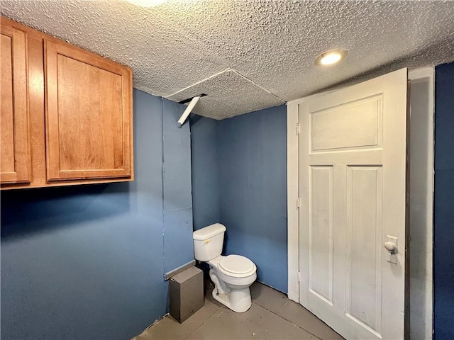 bathroom featuring a textured ceiling, concrete floors, and toilet