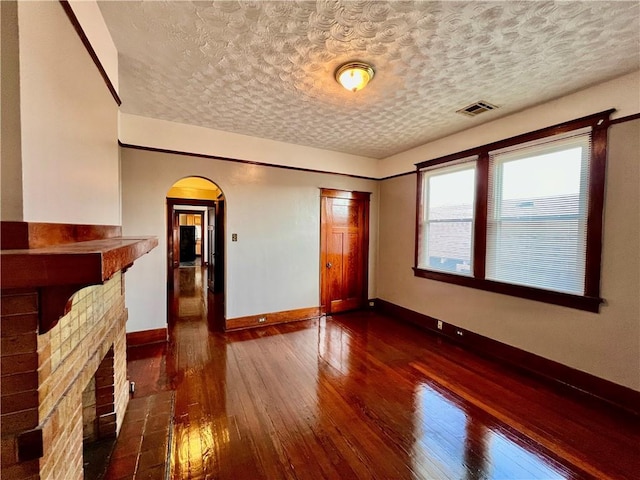 unfurnished living room featuring dark wood-type flooring and a textured ceiling