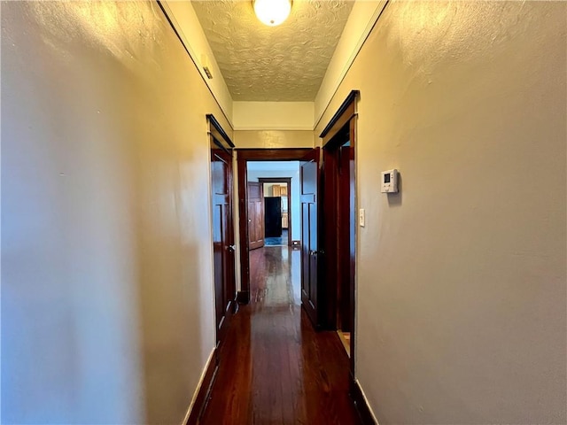 hall with dark hardwood / wood-style flooring and a textured ceiling