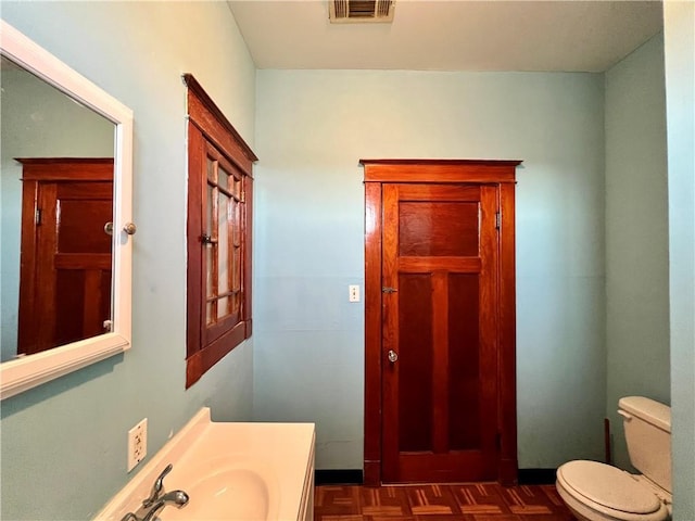 bathroom featuring parquet floors, sink, and toilet