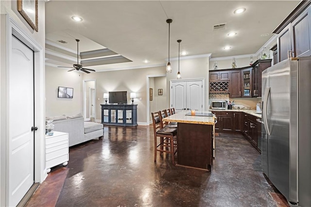 kitchen featuring pendant lighting, appliances with stainless steel finishes, a kitchen island, dark brown cabinetry, and a kitchen bar