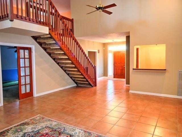 interior space with a towering ceiling, tile patterned flooring, and ceiling fan