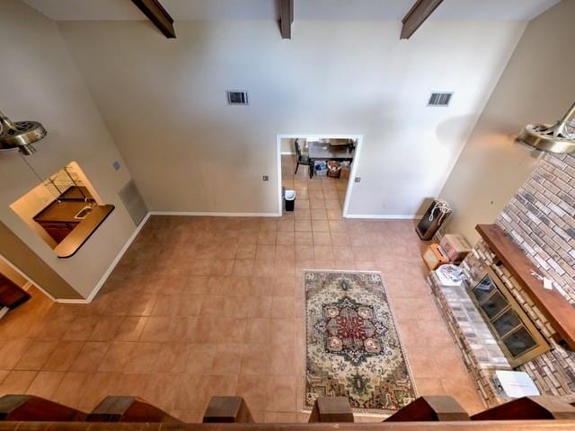 unfurnished living room with tile patterned floors, high vaulted ceiling, and beamed ceiling