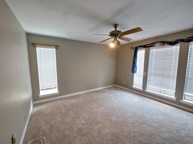 spare room with a wealth of natural light, ceiling fan, and carpet