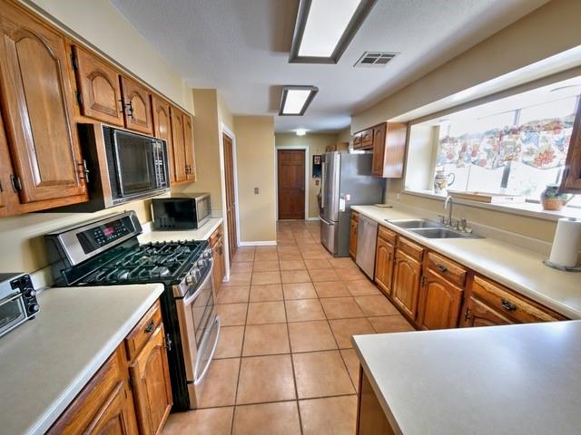 kitchen with light tile patterned flooring, appliances with stainless steel finishes, and sink