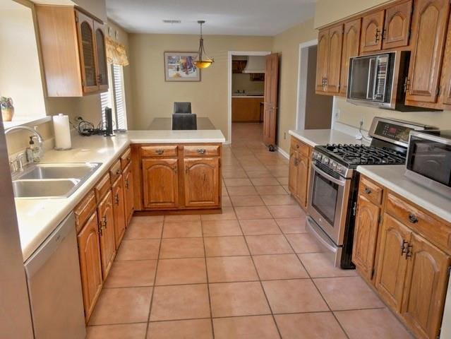 kitchen featuring appliances with stainless steel finishes, pendant lighting, light tile patterned floors, and sink