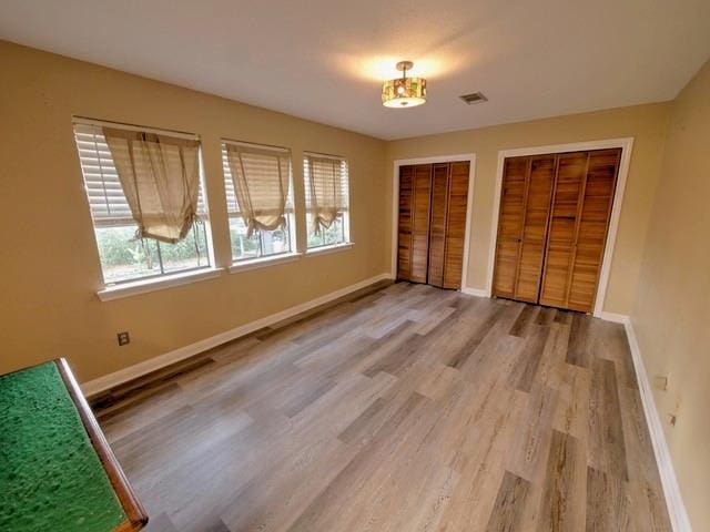 unfurnished bedroom featuring two closets and wood-type flooring