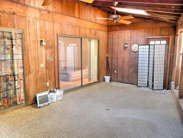 interior space featuring ceiling fan, vaulted ceiling with beams, and carpet floors