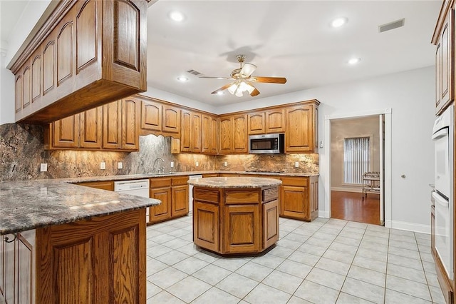 kitchen featuring ceiling fan, light hardwood / wood-style flooring, tasteful backsplash, white dishwasher, and sink