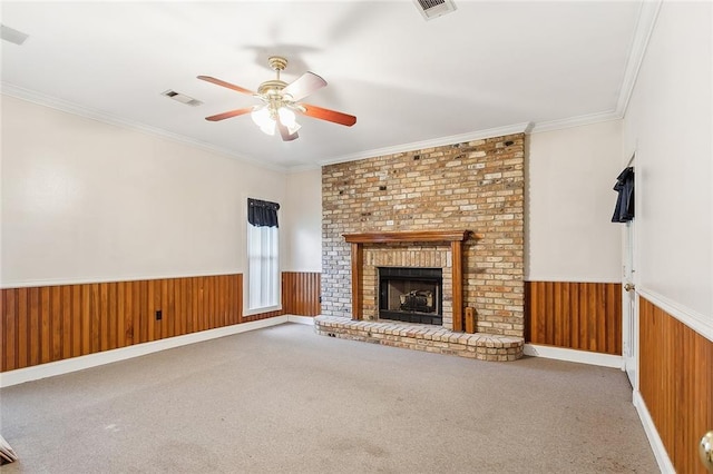 unfurnished living room with ceiling fan, ornamental molding, a brick fireplace, and carpet flooring