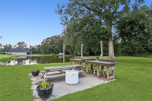 surrounding community featuring a patio area, a water view, and a lawn