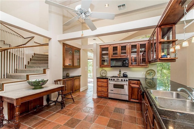 kitchen with sink, stainless steel stove, dark tile patterned floors, and ceiling fan