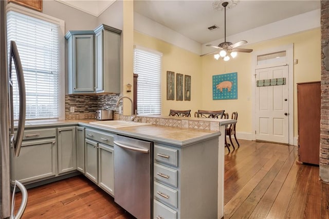 kitchen featuring ceiling fan, kitchen peninsula, stainless steel dishwasher, and wood-type flooring