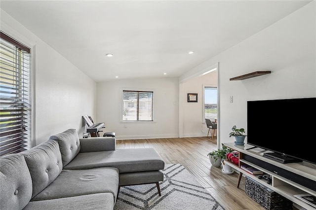 living room with light wood-type flooring, vaulted ceiling, and plenty of natural light