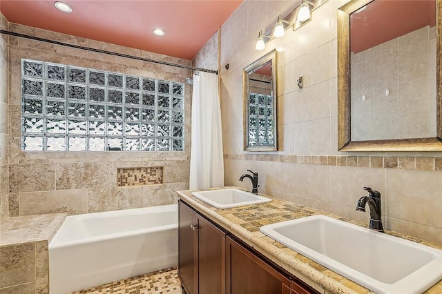 bathroom featuring a tub to relax in, double sink vanity, tile patterned flooring, and tile walls