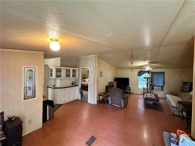 living room with ceiling fan, lofted ceiling, wood-type flooring, and a textured ceiling