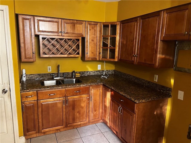 kitchen featuring sink, dark stone counters, and light tile patterned flooring