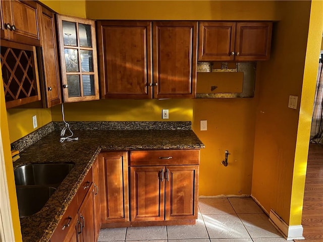 kitchen featuring dark stone counters, light tile patterned floors, and sink