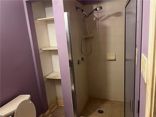 bathroom with tile patterned flooring, tiled shower, and toilet