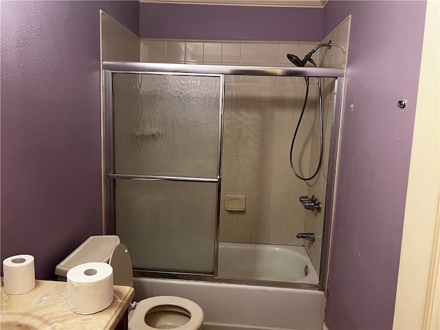 bathroom featuring combined bath / shower with glass door and toilet